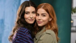 Duas mulheres brancas, uma ao lado da outras. Uma tem cabelo castanho e a outra cabelo ruivo.