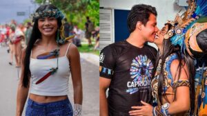 Imagem composta por duas fotos lado a lado. À esquerda, uma mulher sorri ao ar livre durante um evento cultural, usando top branco, saia azul estampada e um cocar delicado com penas coloridas na cabeça e no colar, com pessoas desfocadas ao fundo. À direita, um casal se beija em ambiente interno; o homem veste camiseta preta com estampa colorida e a mulher usa uma fantasia elaborada com cocar grande de penas azuis, acessórios indígenas e roupa azul e dourada, demonstrando carinho e proximidade.