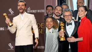 Montagem com duas fotos do Globo de Ouro. À esquerda, um homem usando terno branco segura o troféu dourado e sorri em frente a um painel do evento. À direita, um grupo de homens e mulheres vestidos de gala posa junto, sorrindo, enquanto um deles segura o troféu do Globo de Ouro em um ambiente interno elegante.
