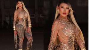 Andress Urach com fantasia de carnaval. Mulher branca, loira, cabelo liso longo, fantasia de correntes pelo corpo todo.