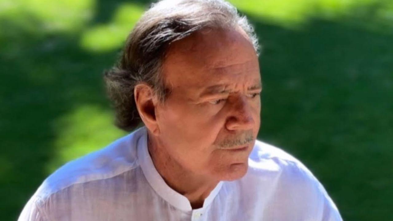 Homem branco, idoso, calvo, com camisa branca ao ar livre.