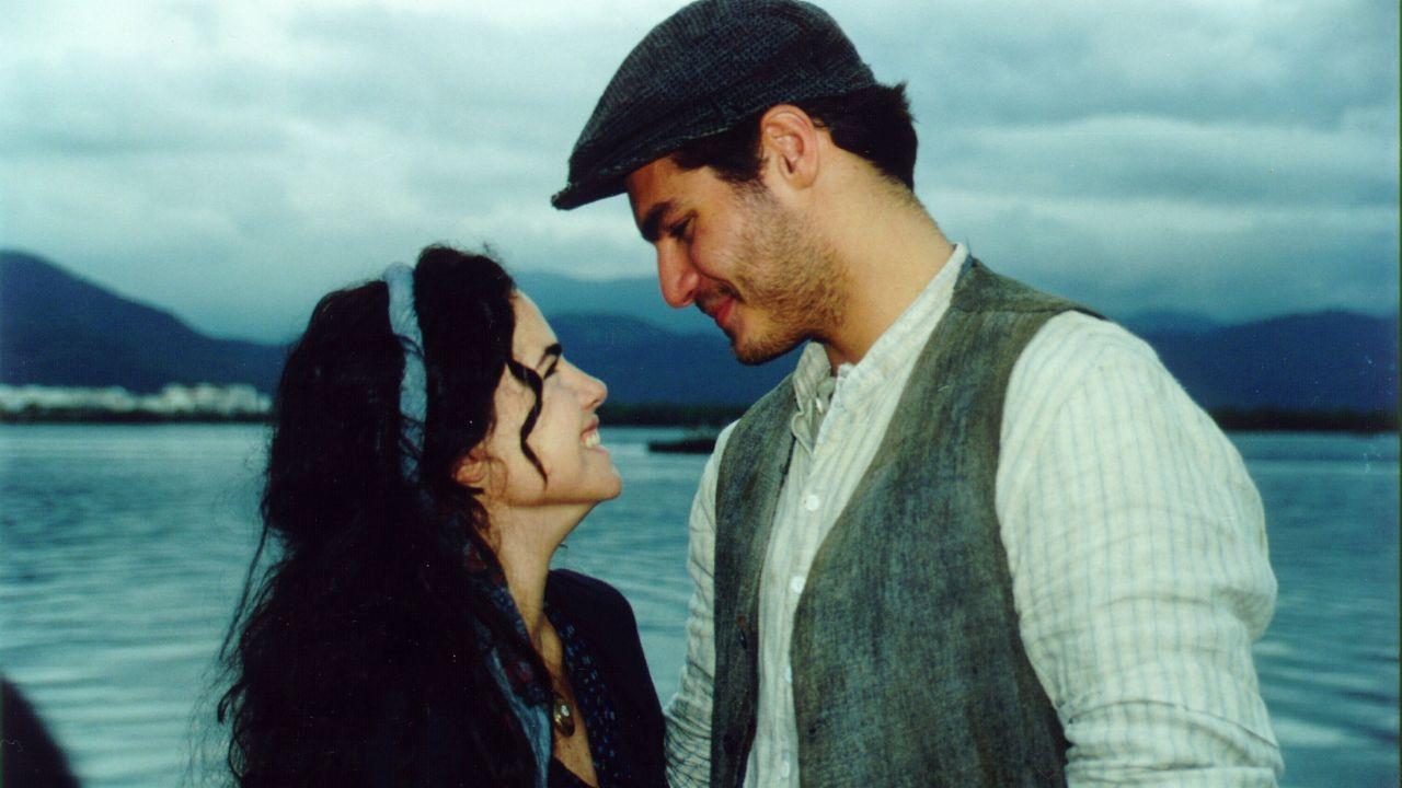 Ana Paula Arósio e Thiago Lacerda em cena da novela Terra Nostra. Eles estão de perfil e olhando para o rosto do outro.