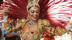Juliana Paes com fantasia vermelha de carnaval cheia de brilho e plumas.