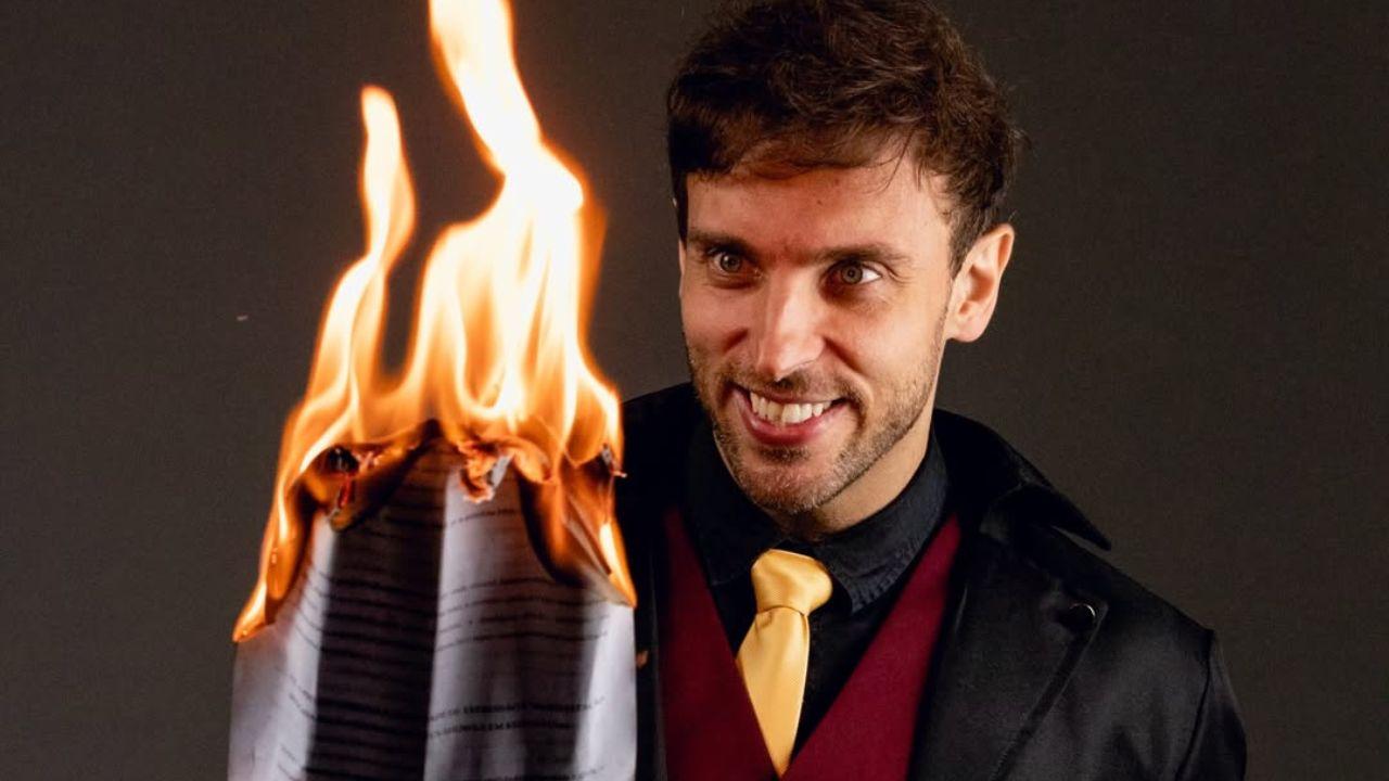 Leo Lins queimando um papel com rosto esquisito.