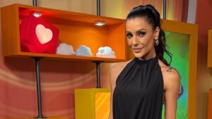 Ceci Ribeiro. Mulher branca, cabelo liso longo preso em rabo de cavalo e usando vestido preto.
