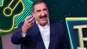 Foto mostra o apresentador Ratinho. Homem branco, bigode, gordo, cabelo preto e usando terno azul.