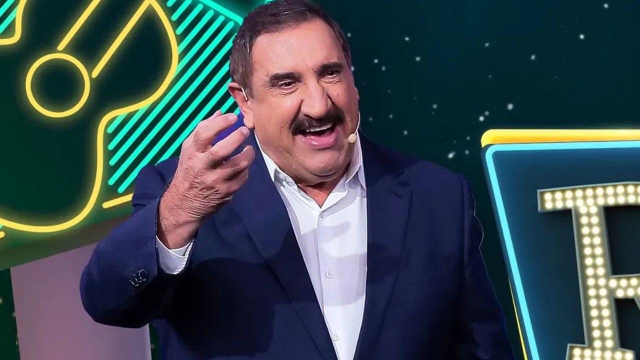 Foto mostra o apresentador Ratinho. Homem branco, bigode, gordo, cabelo preto e usando terno azul.