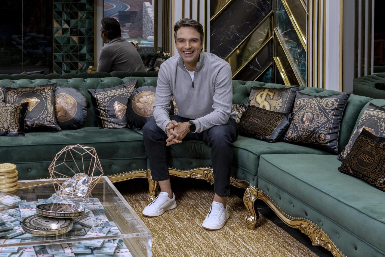 Tadeu Schimdt. Homem branco, cabelo castanho, camiseta preta sorrindo, ao fundo desfocado.