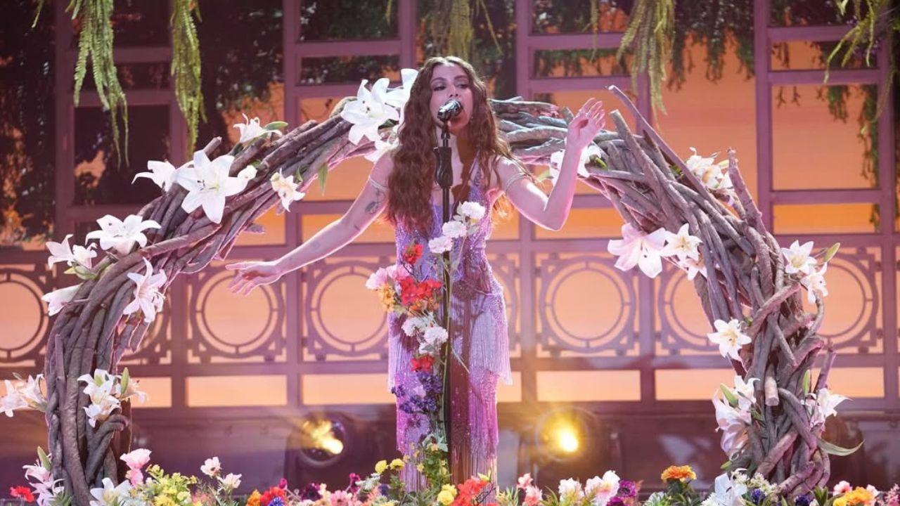 Anitta cantando no palco decorado com plantas e galhos de árvores.