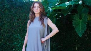 Atriz Letícia Spiller. Mulher branca, cabelo loiro ondulado, usando vestido cinza.