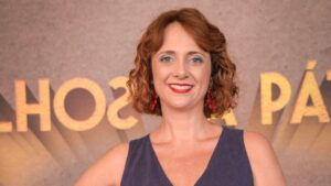 Atriz Letícia Isnard. Mulher branca, loira, cabelo loiro cacheado.