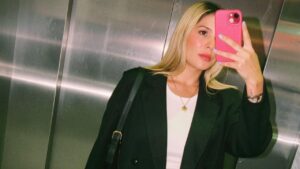 Influenciadora Paola Márquez. Mulher branca, loira, cabelo liso, tirando foto na frente do espelho.