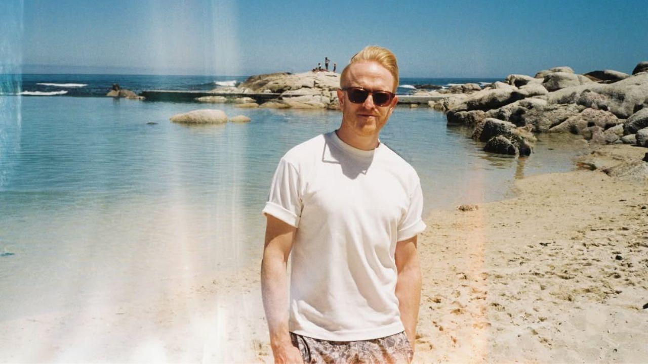 Owain Rhys Davies. Homem branco, calvo, loiro, usando uma camiseta preta.