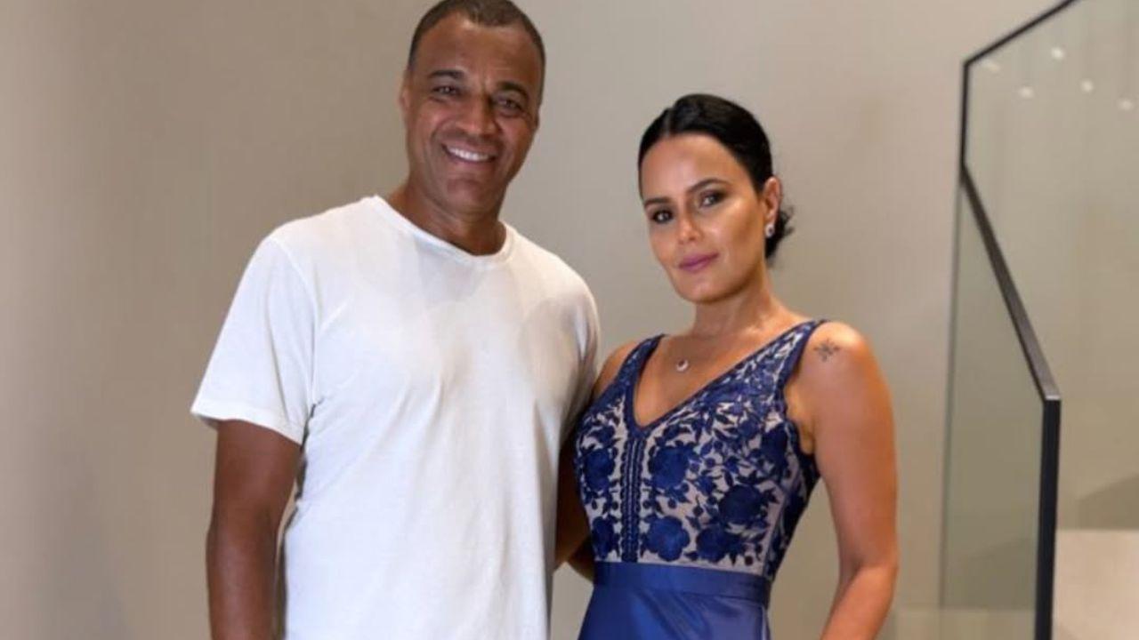 Denilson e Luciele Camargo na frente de uma escada usando roupas de gala.