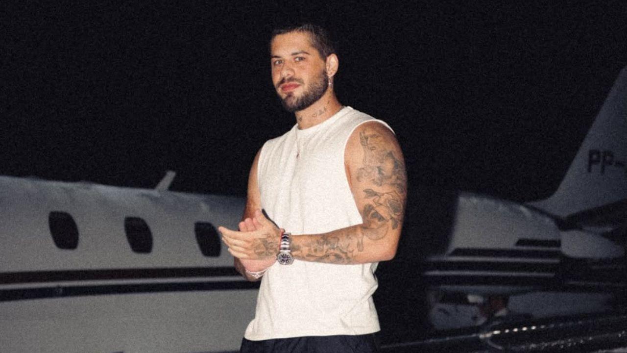 Zé Felipe. Homem branco, cabelo curto castanho, usando camiseta branca na frente de um avião.