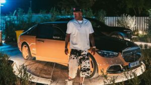 Imagem de Vini Jr. em frente a um carro de luxo