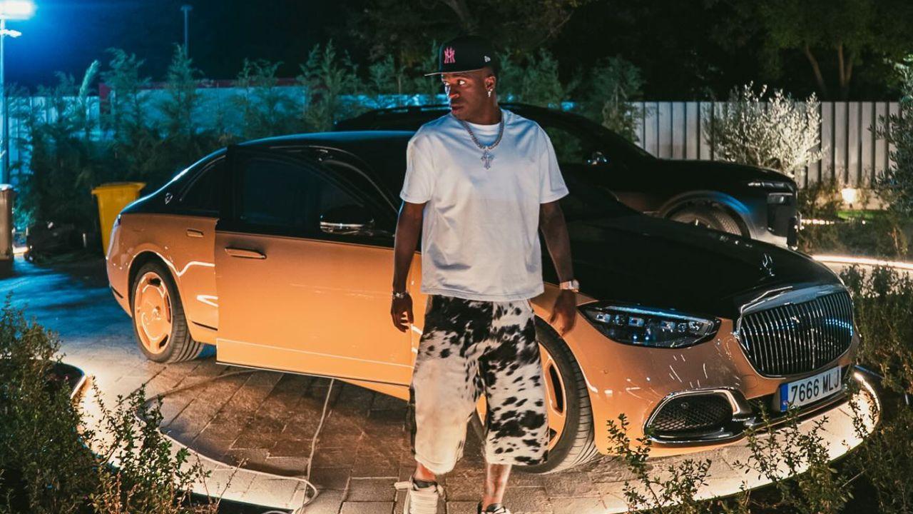 Imagem de Vini Jr. em frente a um carro de luxo