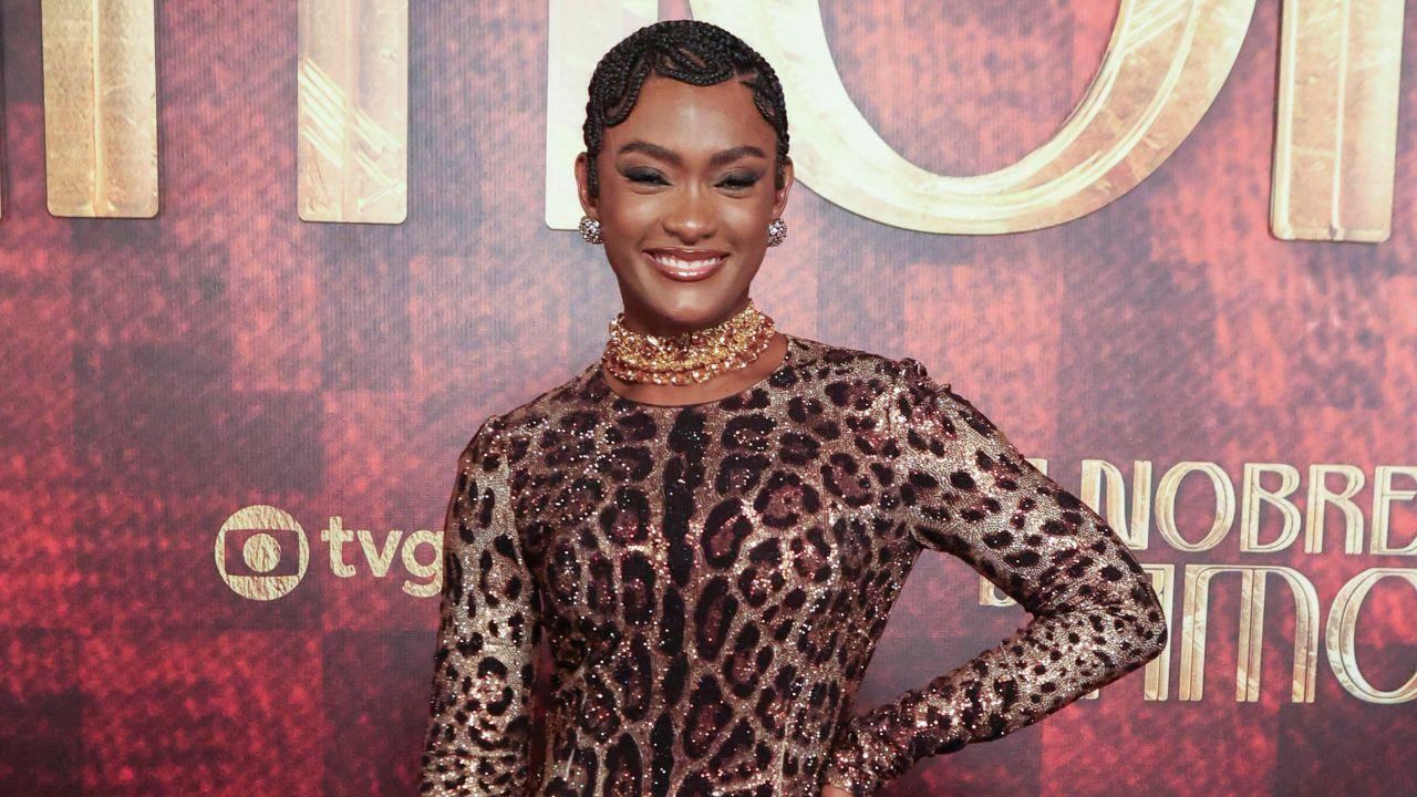 Atriz Erika Januza. Mulher negra, cabelo trançado, vestido de onça e sorrindo.