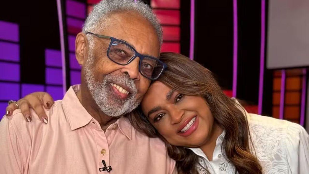 Foto mostra o cantor Gilberto Gil e a filha Preta Gil. Homem negro, idoso, mulher negra, jovem, encostada no ombro do pai.
