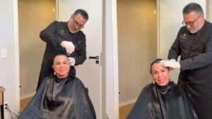 Gretchen sentada na cadeira com um cabelereiro raspando o cabelo dela.