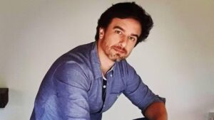 Marco Furlan. Homem branco, cabelo castanho curto, com barba, usando camisa jeans.