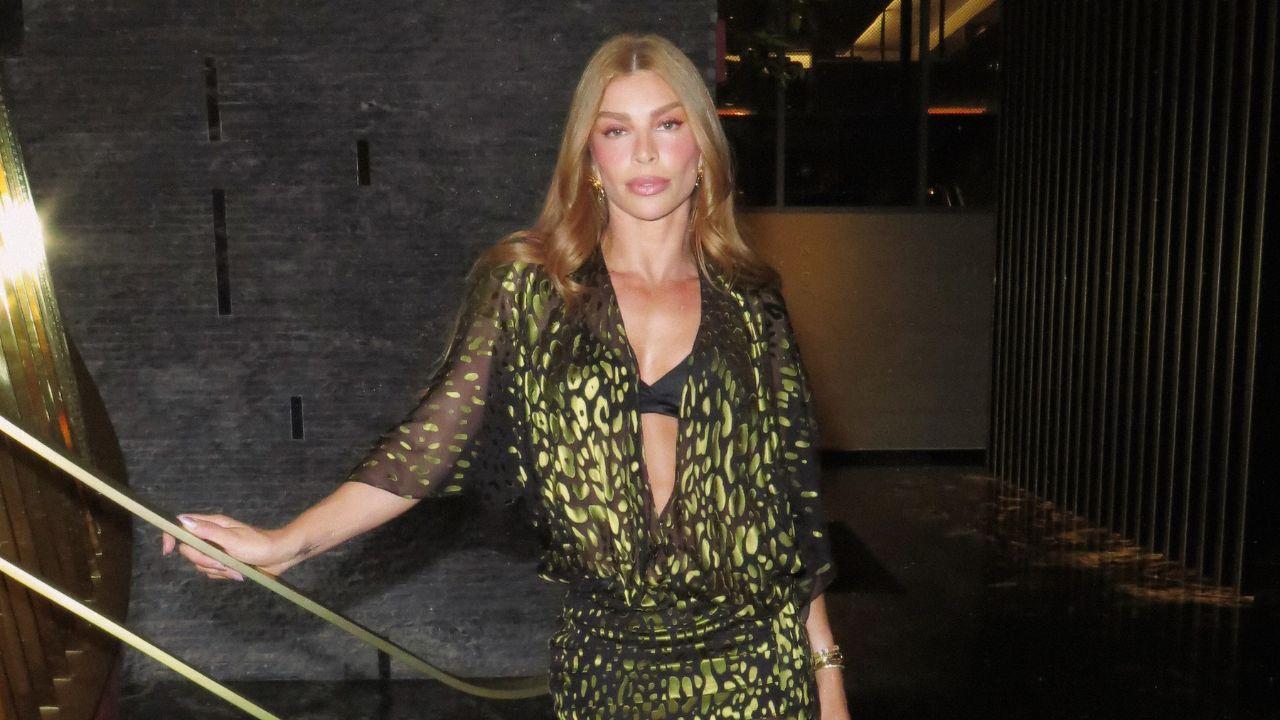 Grazi Massafera com vestido verde estampado em pé, perto de um corrimão.